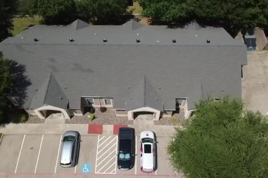 Drone view of a multi-unit apartment building re-roofed by Select Roofing, with its parking lot in front